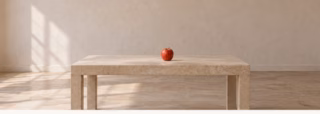A red apple on a table in an empty room lit by a window